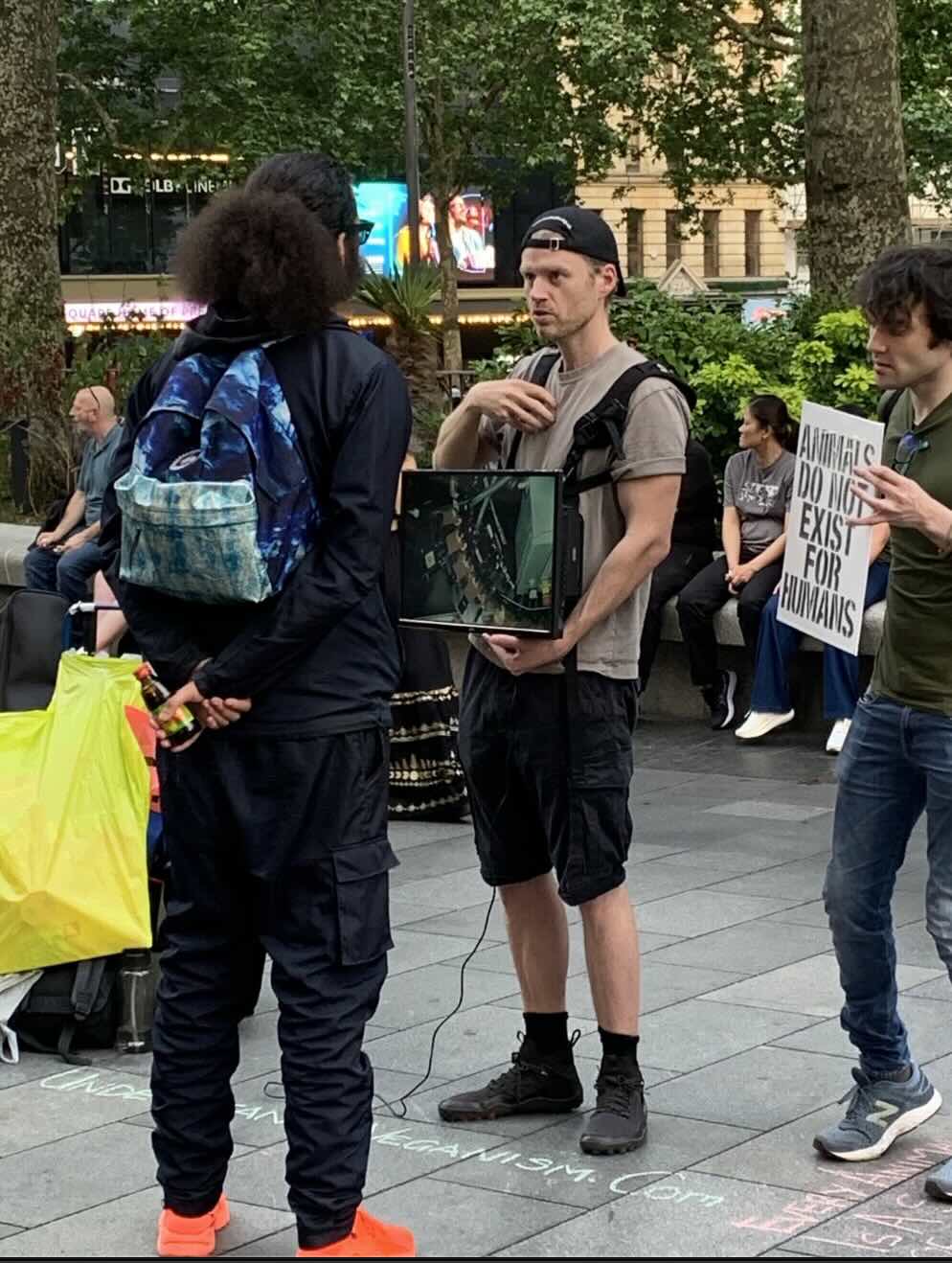 A volunteer holding a screen, talking with someone during a public outreach