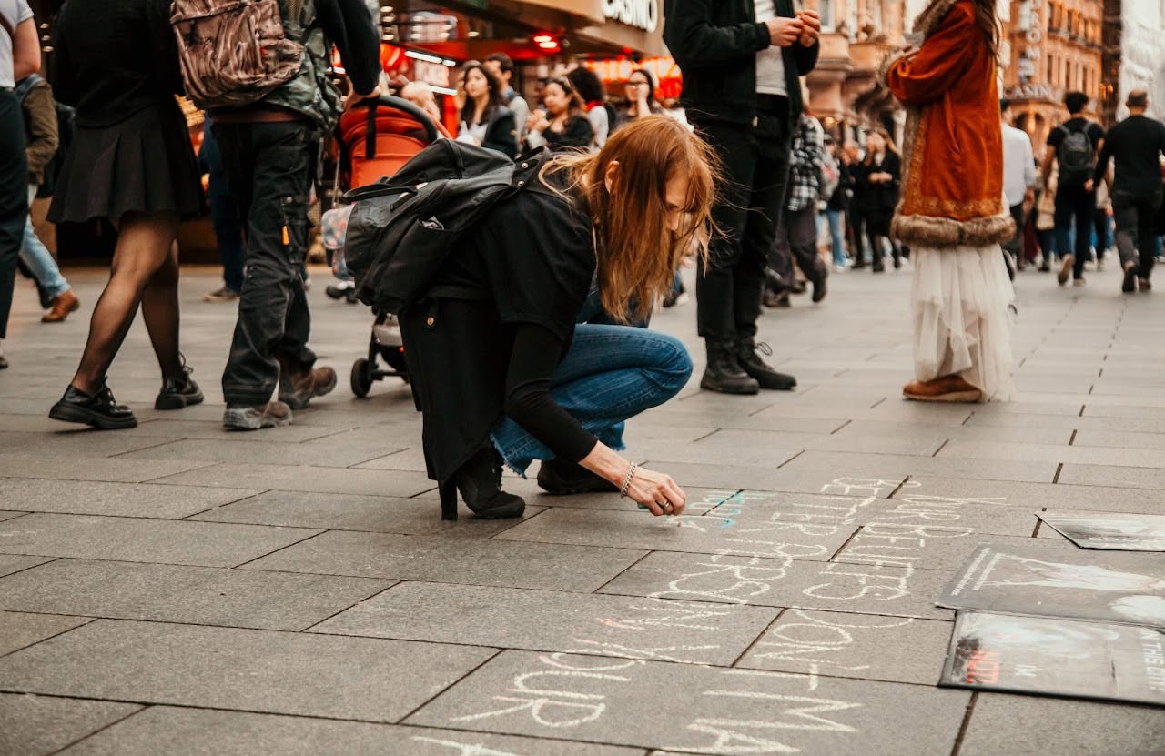 Jo chalking a message on the pavement during outreach